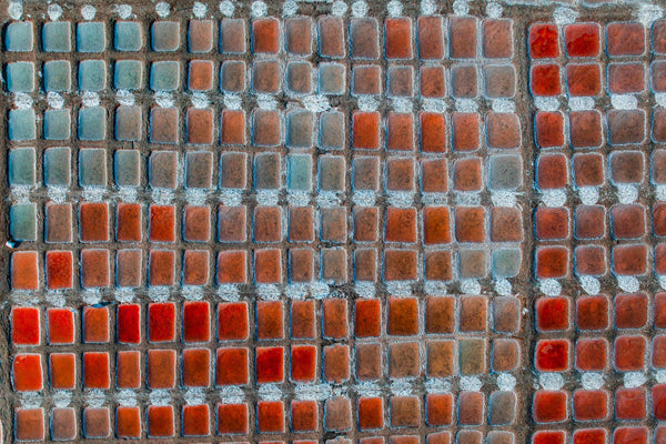 Top-down drone shot of uniform salt basins shifting from blue-green to copper tones, forming a vast abstract grid in Oman.