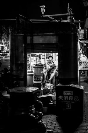 Street scene of a man on the phone in his booth at Bei Xin Qiao Station, Beijing, China.  Fine Art Limited Edition of 28. Photo © Copyright by Sylvère Clerempuy.