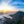 Aerial panorama of Bali’s volcanic highlands at sunrise with a sea of clouds, sun on the horizon, and green ridges in the foreground.