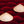 Top-down composition of two Vietnamese conical hats placed on dense red incense bundles in an incense-drying yard.