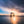 Torii gate of Shirahige Shrine standing in Lake Biwa with the sun shining through and dramatic clouds over the water.