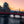 Sunset view of Matsumoto Castle with a red bridge over the moat and a person with a bicycle on the path in the foreground.