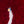 Drone view of a worker walking a narrow gray aisle between dense fields of red incense bundles, seen from directly above.